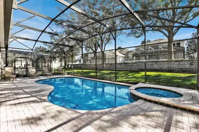 a swimming pool with a pergola next to a house at 7752 Tosteth in Kissimmee