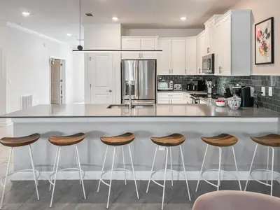 a kitchen with white cabinets and a counter with stools at Happily Ever Home, Your Family Dream Beyond Disney in Kissimmee