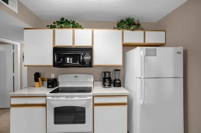 a kitchen with white cabinets and a white refrigerator at Ground Level Condo with Garden Patio in Kissimmee
