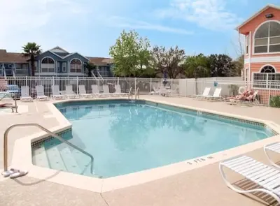 a swimming pool at a resort with chairs at Ground Level Condo with Garden Patio in Kissimmee