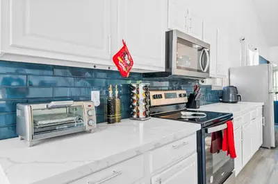 a kitchen with white cabinets and a microwave at Beautiful 5BR 4 baths Themed home near Disney and Universal, Private Pool, Gameroom, baby Crib and more in Kissimmee