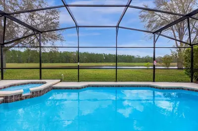 a large swimming pool with a large glass building at Bluelakeview Luxury Villa with Private Pool & Spa plus Lake Views, BBQ, Games Room in Orlando
