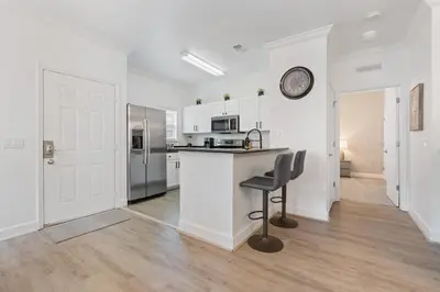 a white kitchen with a counter and a chair at Cozy 4Bedrooms At Lucaya- 7 miles from Disney in Kissimmee