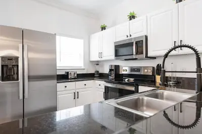 a kitchen with white cabinets and a stainless steel refrigerator at Cozy 4Bedrooms At Lucaya- 7 miles from Disney in Kissimmee