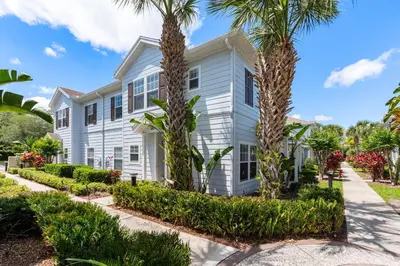 a white house with palm trees in front of it at Cozy 4Bedrooms At Lucaya- 7 miles from Disney in Kissimmee