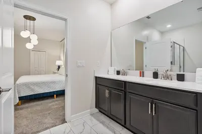 a bathroom with a sink and a mirror and a bed at New Home 9 Bedrooms and 5 Bath At Storey Lake in Kissimmee