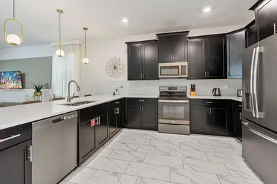 a kitchen with black cabinets and stainless steel appliances at New Home 9 Bedrooms and 5 Bath At Storey Lake in Kissimmee