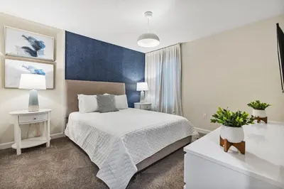 a bedroom with a white bed and a blue wall at New Home 9 Bedrooms and 5 Bath At Storey Lake in Kissimmee