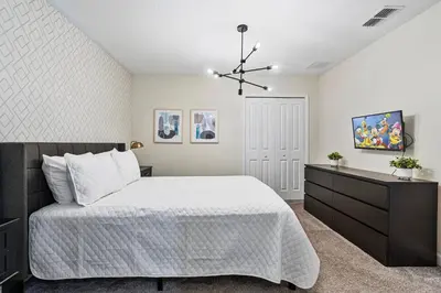 a bedroom with a large bed and a dresser at New Home 9 Bedrooms and 5 Bath At Storey Lake in Kissimmee