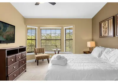 a bedroom with a bed and a tv and windows at Your Summer Getaway Awaits - Townhome by Disney! in Orlando