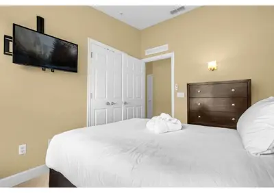 a bedroom with a white bed and a flat screen tv at Your Summer Getaway Awaits - Townhome by Disney! in Orlando