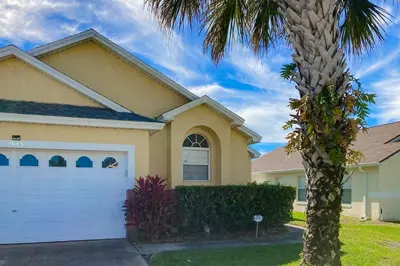 a house with a palm tree in front of it at Disney 15 Min - Sleeps 8 - Private Pool in Kissimmee