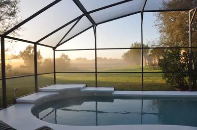 a swimming pool in a glass house with a view of a golf course at The Oasis in Orlando