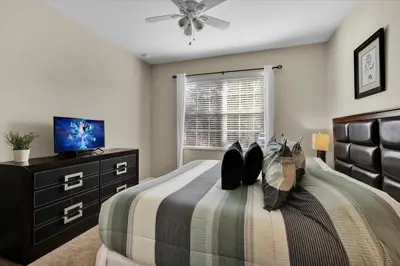 a bedroom with a bed with a dresser and a tv at 2920 Banana Palm in Kissimmee