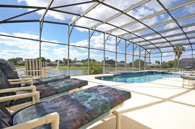 a glass house with a swimming pool and a patio at Lake House at Formosa home in Orlando