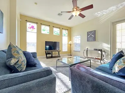 a living room with two blue couches and a ceiling fan at Lake House at Formosa home in Orlando