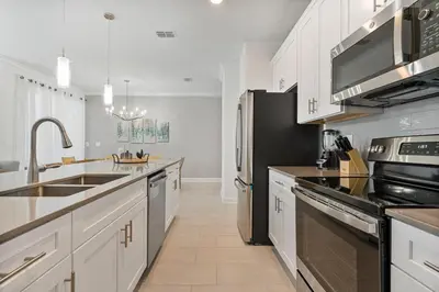 a kitchen with white cabinets and stainless steel appliances at New Home 4 Bedrooms 3 Bathrooms At Storey Lake in Kissimmee