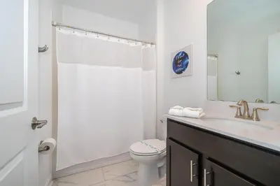 a white bathroom with a toilet and a sink at 4156DS VILLA 5 BED/5 BA in Kissimmee