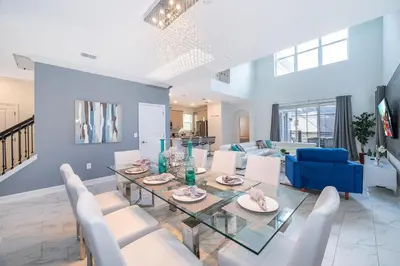 a dining room and living room with a glass table and chairs at 2668DR VILLA 5 BED/5 BA (SANITIZED) in Kissimmee