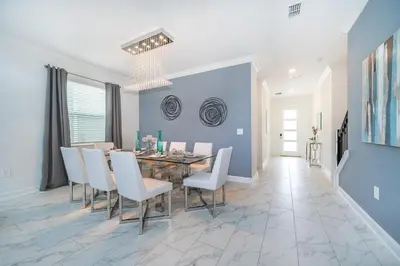 a dining room with a table and white chairs at 2668DR VILLA 5 BED/5 BA (SANITIZED) in Kissimmee