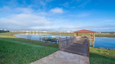 a dock with a gazebo next to a lake at 2472PB TOWNHOUSE 4 BEDROOMS & 3 BATHROOMS + POOL in Kissimmee