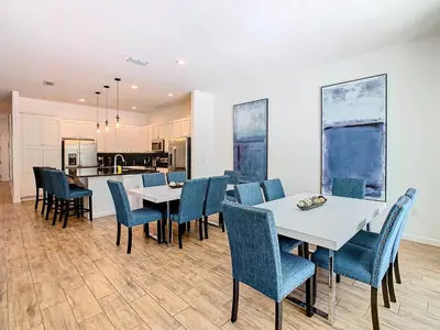 a dining room with white tables and blue chairs at Elegant Villa 12BD-12BA Vacation Haven BV368 in Kissimmee
