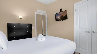 a bedroom with a white bed with a tv on the wall at Summer Deal - Relax & Unwind, Townhome by Disney! in Orlando