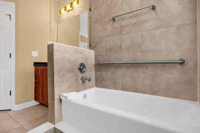 a bathroom with a white tub and a shower at Sunny Summer Awaits - Renovated Townhome by Disney! in Orlando