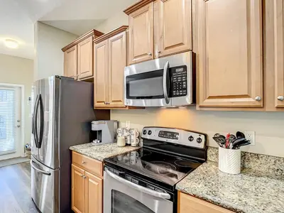 a kitchen with stainless steel appliances and wooden cabinets at Paradise Palms Resort Townhome Close to Disney in Kissimmee