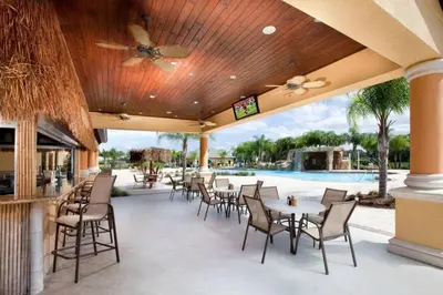 a patio with tables and chairs and a pool at Paradise Palms Resort Townhome Close to Disney in Kissimmee