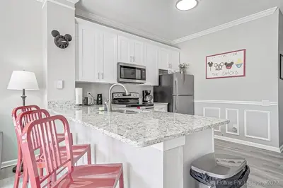 a kitchen with a counter and two pink chairs at SilverPalm Disney Home, Free Amenities, 3mi Disney in Kissimmee