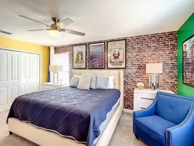 a bedroom with a bed and a blue chair at StoreyLake Imagination Villa, 5mi Disney Universal in Kissimmee