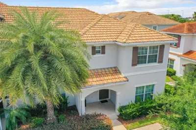a white house with a palm tree in front of it at Storey Lake Dreamy Townhome, 5 mi Disney Universal in Kissimmee