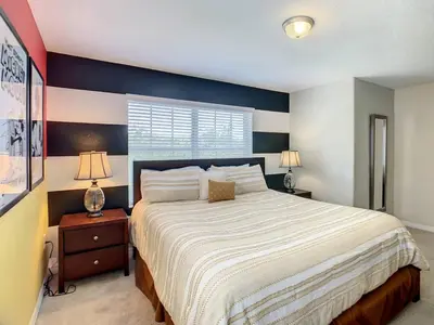 a bedroom with a large bed with a blue accent wall at Storey Lake Dreamy Townhome, 5 mi Disney Universal in Kissimmee