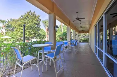 a patio with chairs and tables and a ceiling fan at Enchanted Jungle Themed Home Pool 3mi to Disney in Kissimmee