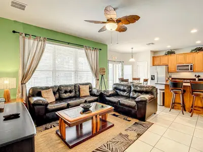 a living room with leather couches and a kitchen at Windsor Hills Themed Home Pool Spa 2.5mi Disney in Orlando