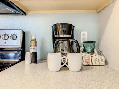 a coffee maker and two cups on a kitchen counter at Windsor Hills Themed Condo, 2.5mi to Disney in Orlando