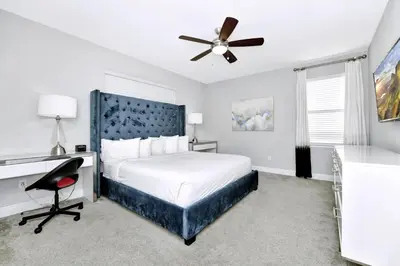 a bedroom with a bed and a desk and a ceiling fan at Stylish Home With Private Pool, Themed And Game Room With Waterpark & Resort Access Near Disney At Encore Resorts Reunion - 300Bu in Kissimmee