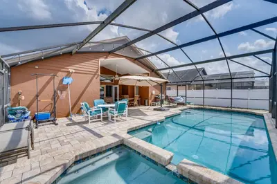a swimming pool with a patio and a building at 4 Mi to Disney Spacious Retreat with Pool and Yard! in Kissimmee