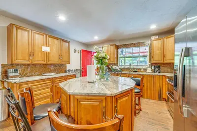 a kitchen with wooden cabinets and a island in it at Orlando-Area Family Oasis with Lanai, Pool and Yard in Orlando