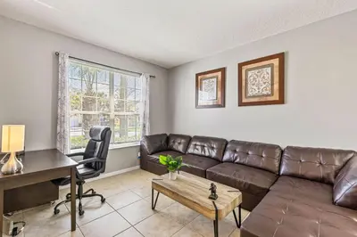 a living room with a brown leather couch and a desk at 7BDM Prvt Pool Villa - Gated Resort 10min to Disney in Kissimmee