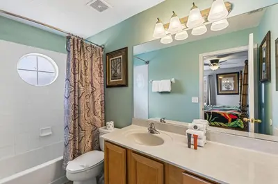 a bathroom with a sink and a toilet and a mirror at 7BDM Prvt Pool Villa - Gated Resort 10min to Disney in Kissimmee