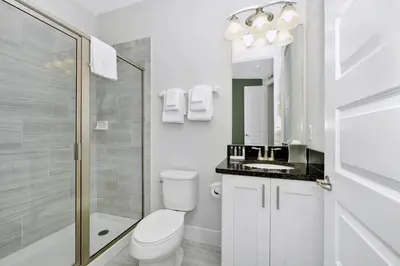 a white bathroom with a toilet and a shower at Elegant Home Near Disney With Game & Themed Rooms With Waterpark & Resort Access At Encore Resorts Reunion - 400La in Kissimmee