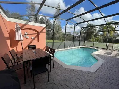 a patio with a swimming pool and a table and a table and chairs at 4 Bedroom 3 Bathroom Terra Verde 111PB in Kissimmee