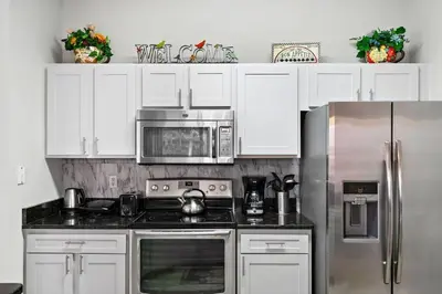a kitchen with white cabinets and a stainless steel refrigerator at 4 Bedroom 3 Bathroom Terra Verde 111PB in Kissimmee