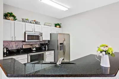 a kitchen with white cabinets and a stainless steel refrigerator at 4 Bedroom 3 Bathroom Terra Verde 111PB in Kissimmee