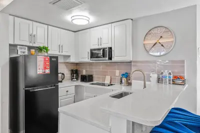 a kitchen with white cabinets and a black refrigerator at Exclusive Ground floor Apartment with Balcony in Orlando