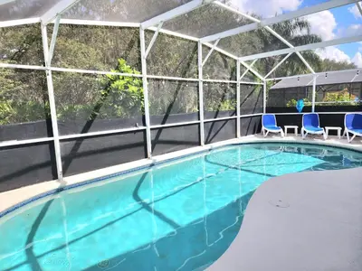 a swimming pool with two blue chairs in a building at Home Close to Disney Parks/Amazing Private Pool in Orlando
