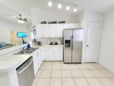 a kitchen with white cabinets and a stainless steel refrigerator at Home Close to Disney Parks/Amazing Private Pool in Orlando