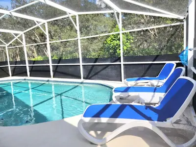 a pair of blue chairs sitting next to a swimming pool at Home Close to Disney Parks/Amazing Private Pool in Orlando